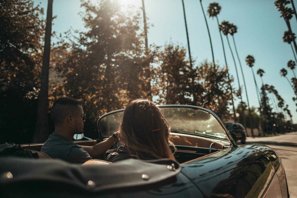 A couple driving a convertible during a honeymoon in California along palm tree-lined streets