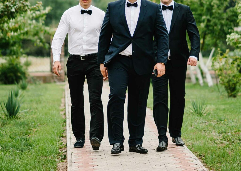 A black-tie optional wedding dress code with three men wearing suits and bow ties
