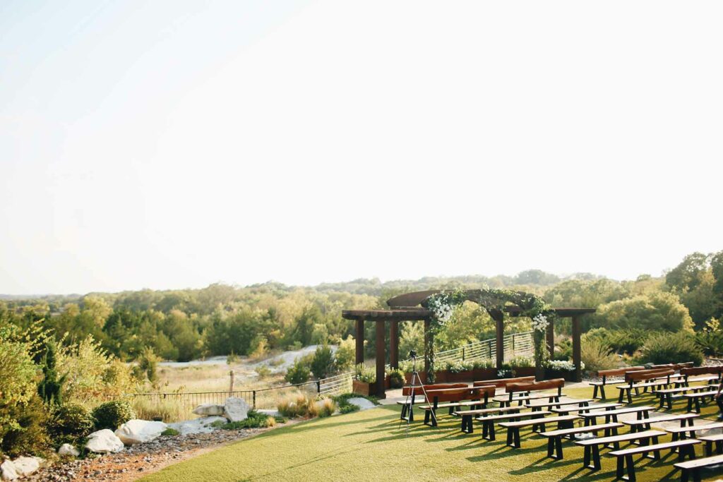 An outdoor wedding ceremony venue with rustic benches overlooking an archway