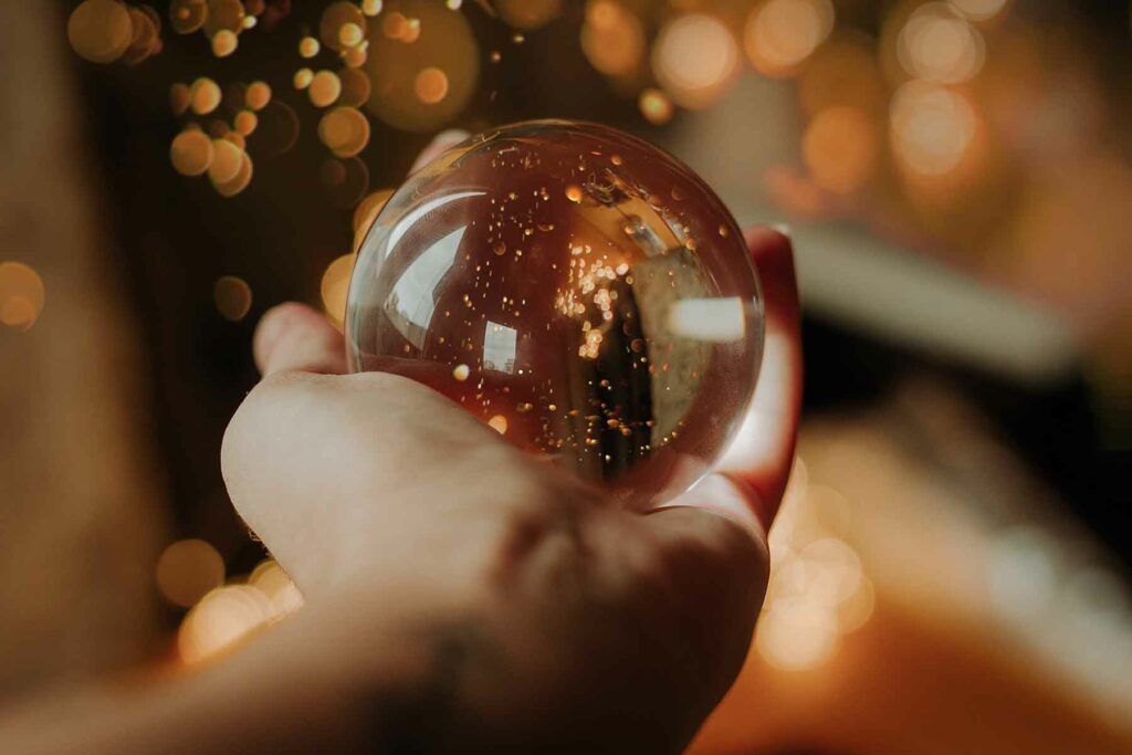 Wedding favor gift idea: An outstretched hand holding a snow globe with glittering lights in the background