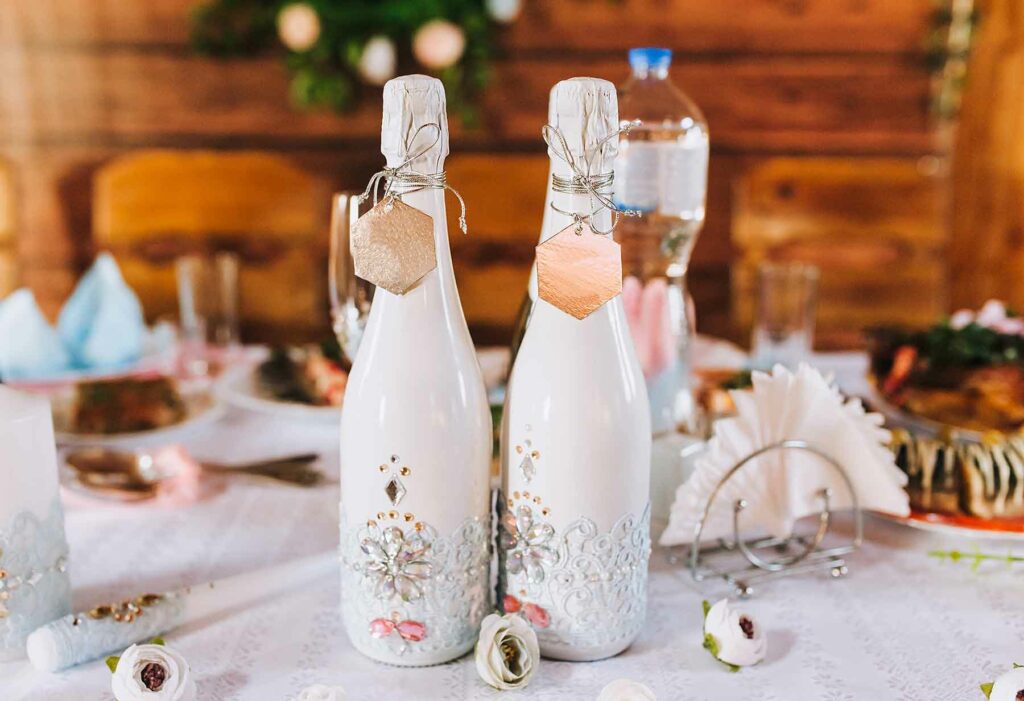 Wedding favor gift idea: Champagne bottles decorated with a wedding theme on a reception table