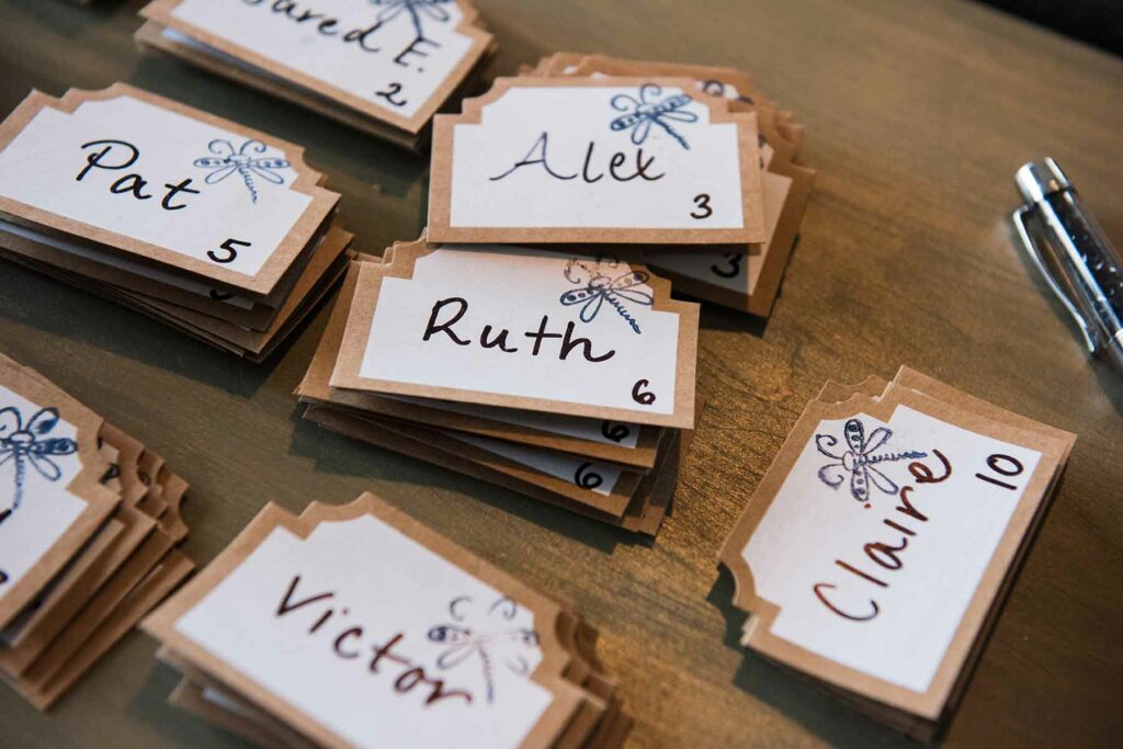 Place cards from a wedding guest list with names and table numbers handwritten