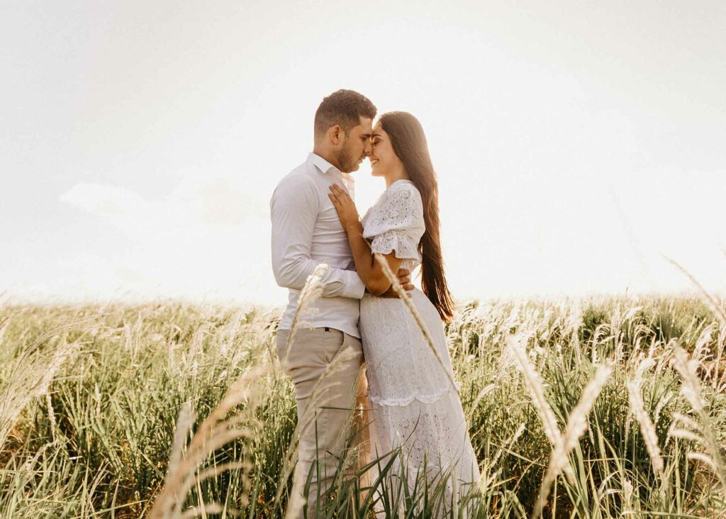 What to Wear in Engagement Photos: A couple wearing white embracing in a meadow