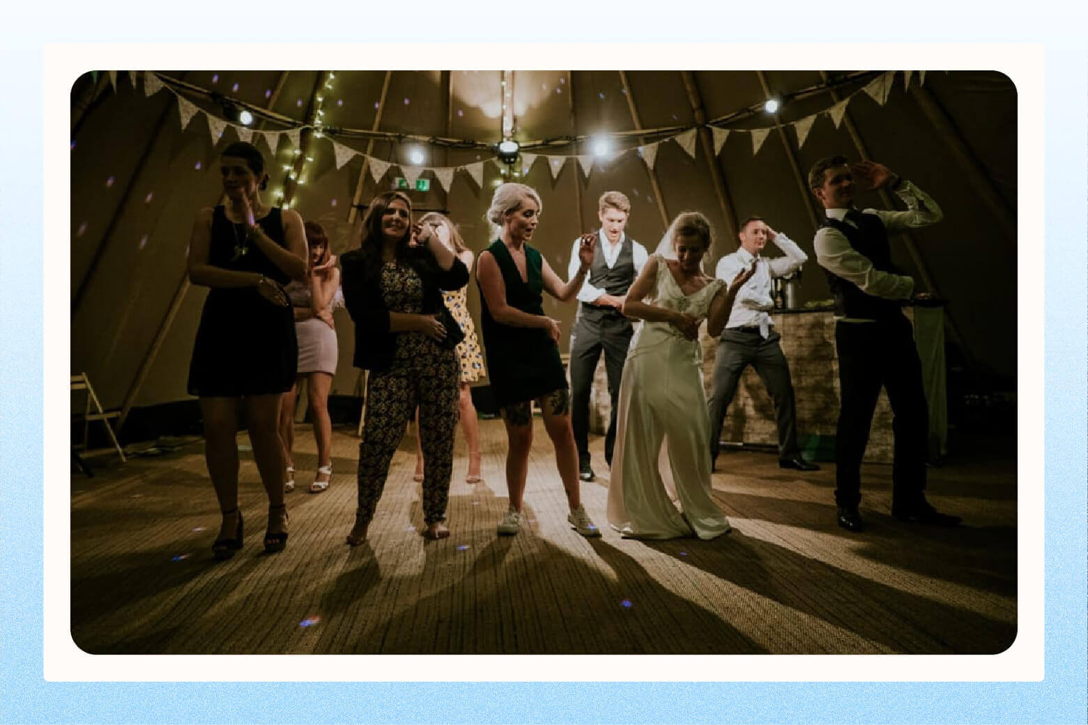 Wide shot of bride, groom, and guests dancing at wedding reception