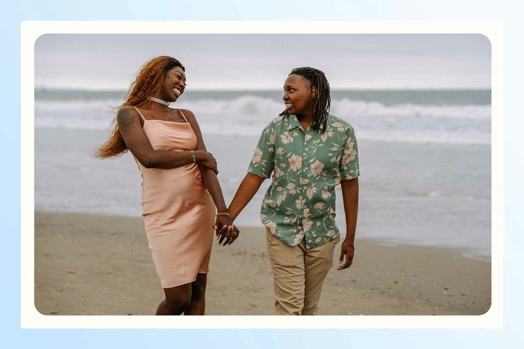 A couple holding hands and walking on the sand before a beach proposal