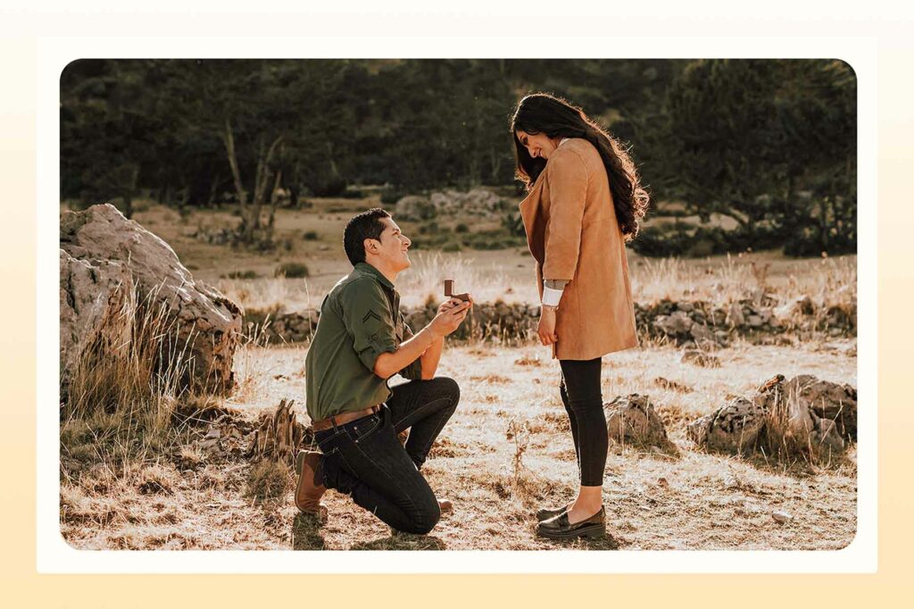 A man kneeling with an open ring box in a national park, about to propose