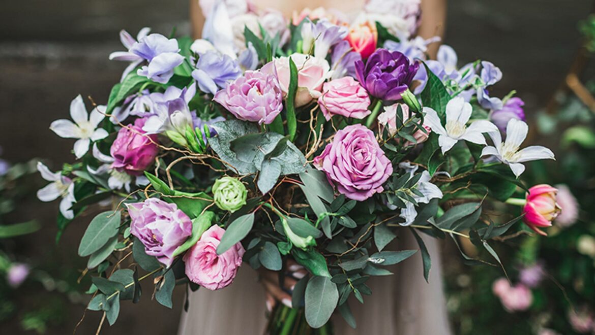 Close up of vibrant wedding bouquet with pink and purple flowers and lots of greenery