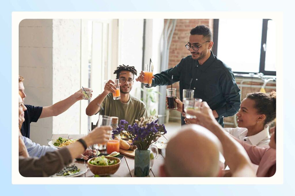 A couple celebrating their engagement with loved ones and raising glasses around a table 