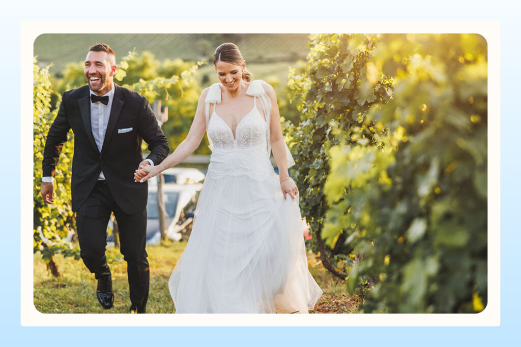 newlywed couple walking through vineyard greenery