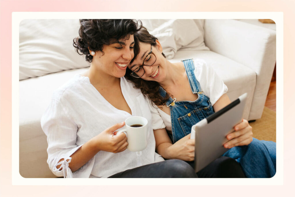 engaged female couple sitting together at home calculating wedding costs