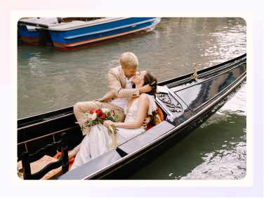 A bride and groom ride in a gondola overlooking a river