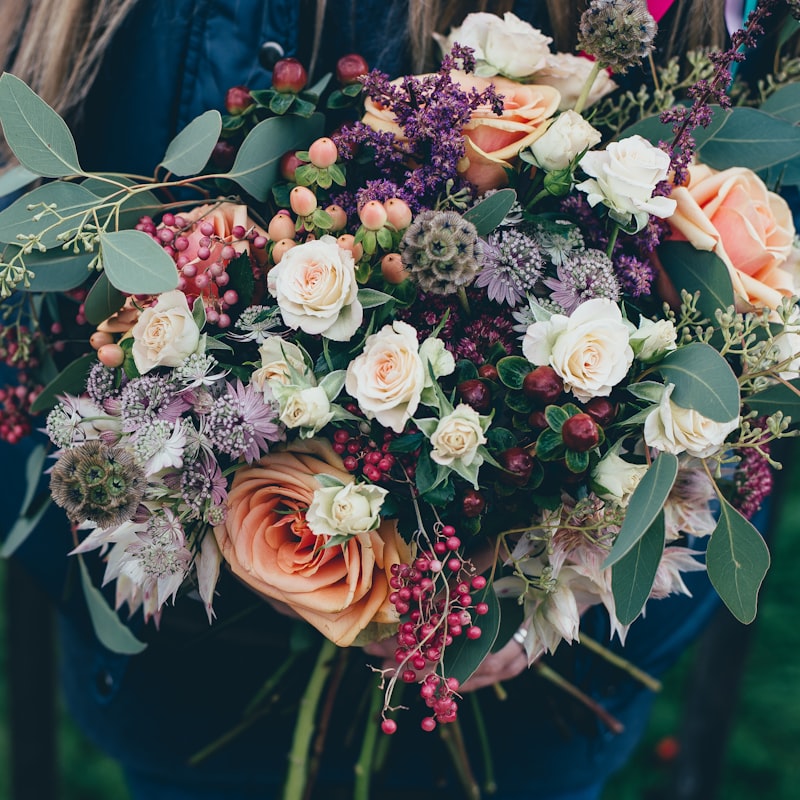 Elegant wedding floral arrangement with white roses and greenery on a reception table