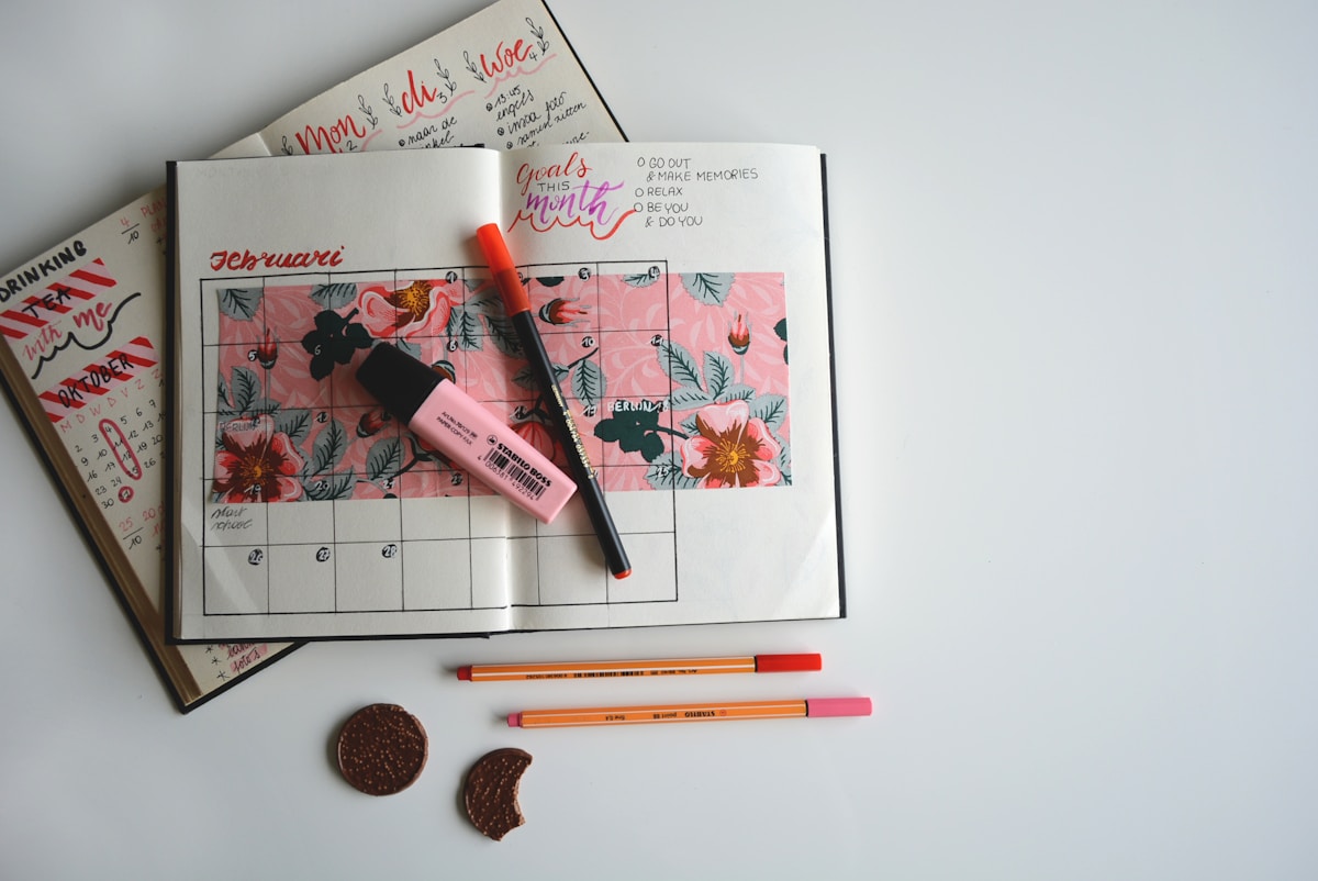 Wedding planning calendar with colored pens marking invitation ordering and mailing dates