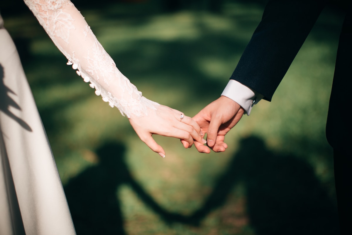 A wedding couple holding hands during an outdoor ceremony surrounded by family and friends