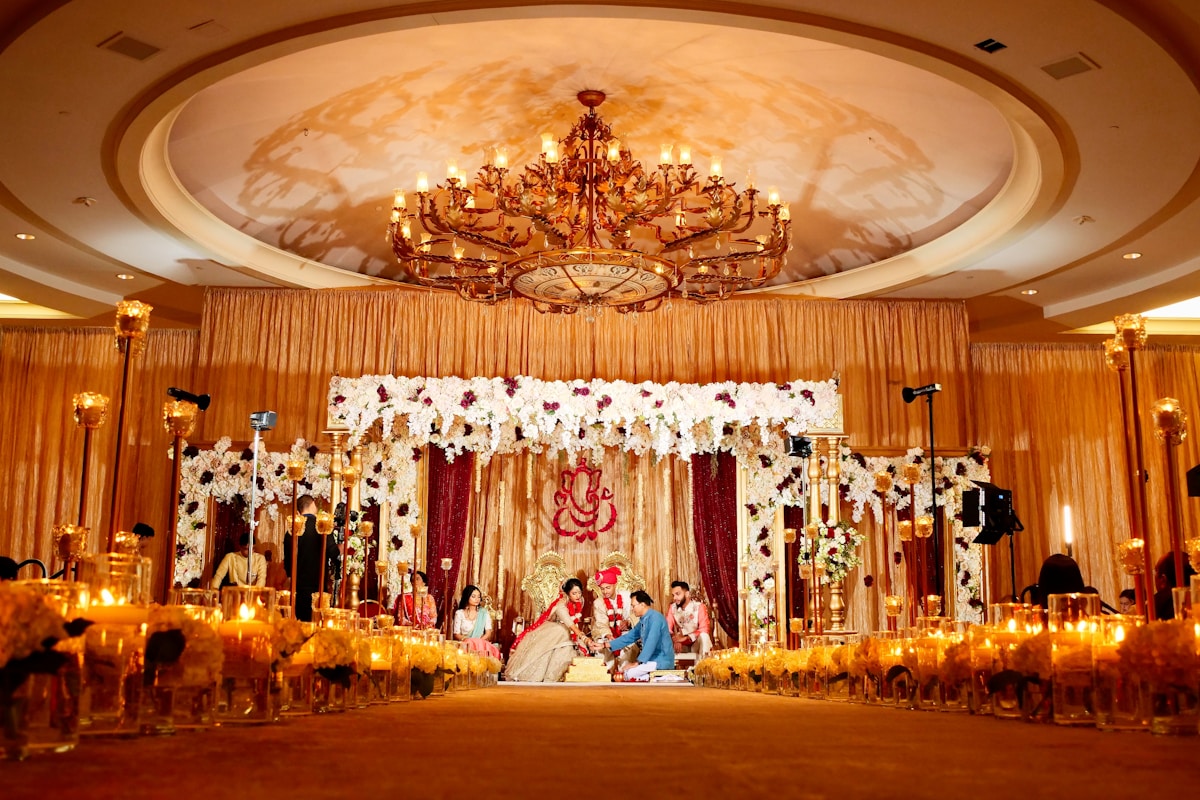A beautifully decorated multicultural wedding ceremony with ornate floral arrangements and warm lighting in an elegant ballroom
