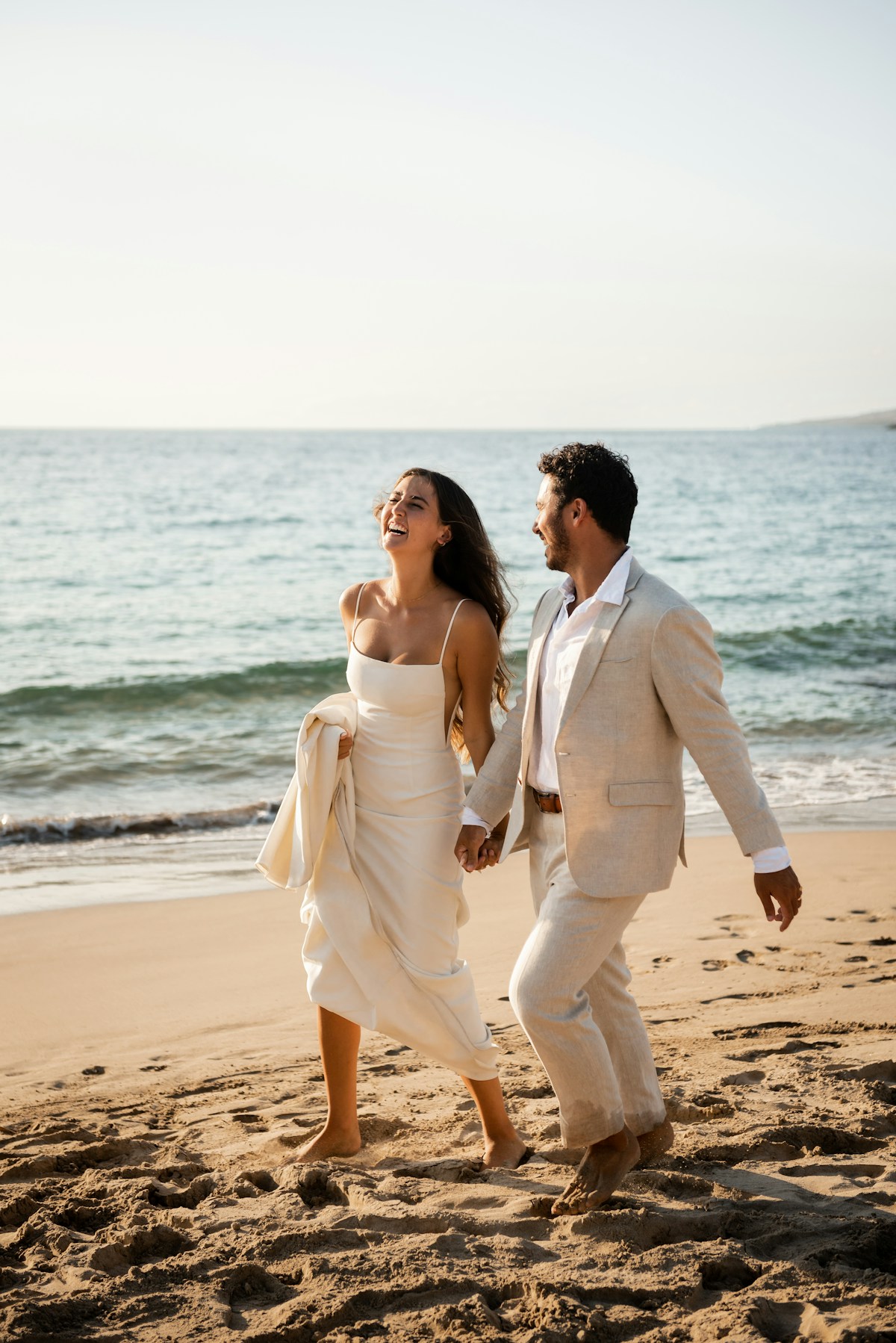 Newlyweds running happily along the beach during their destination wedding