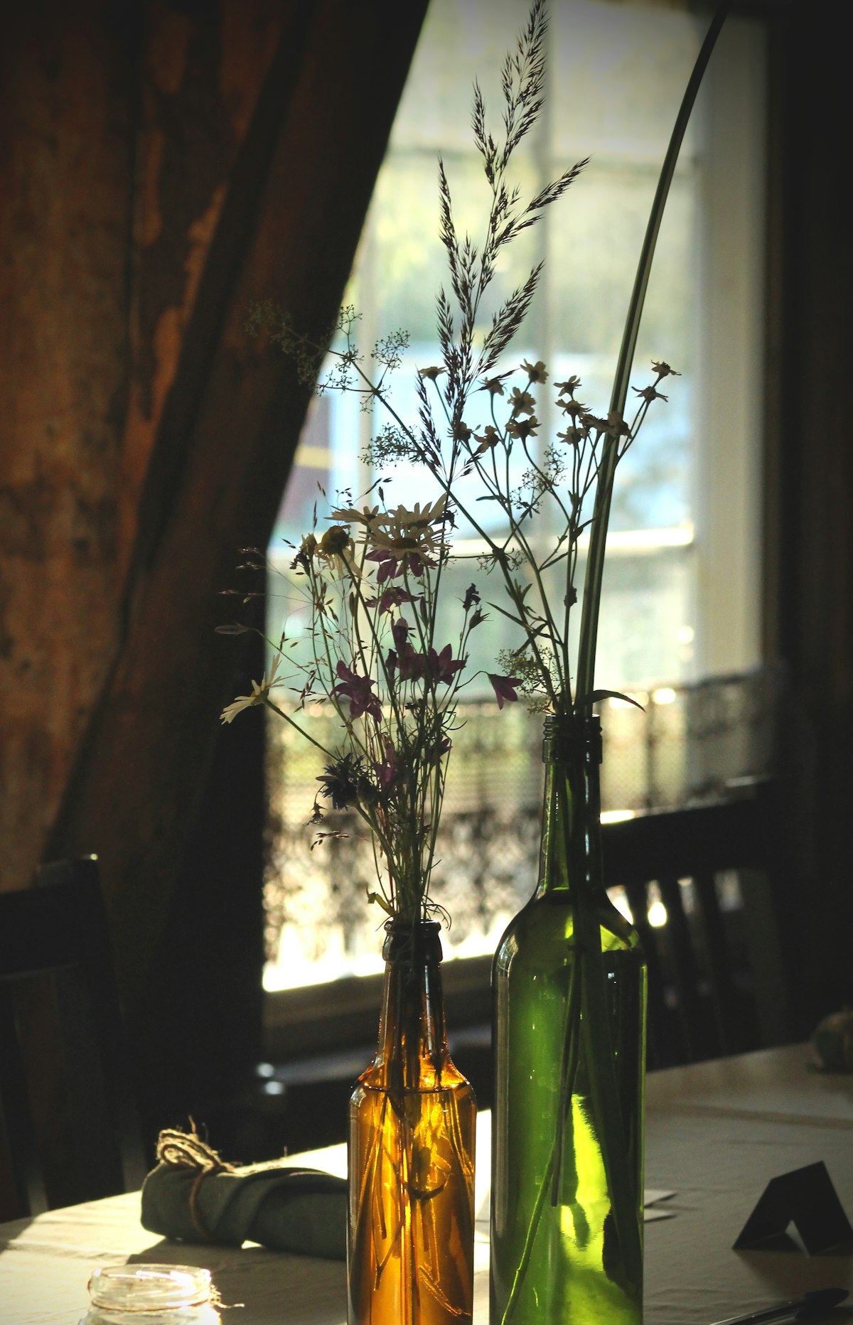 Wildflowers in glass bottles on a wooden table
